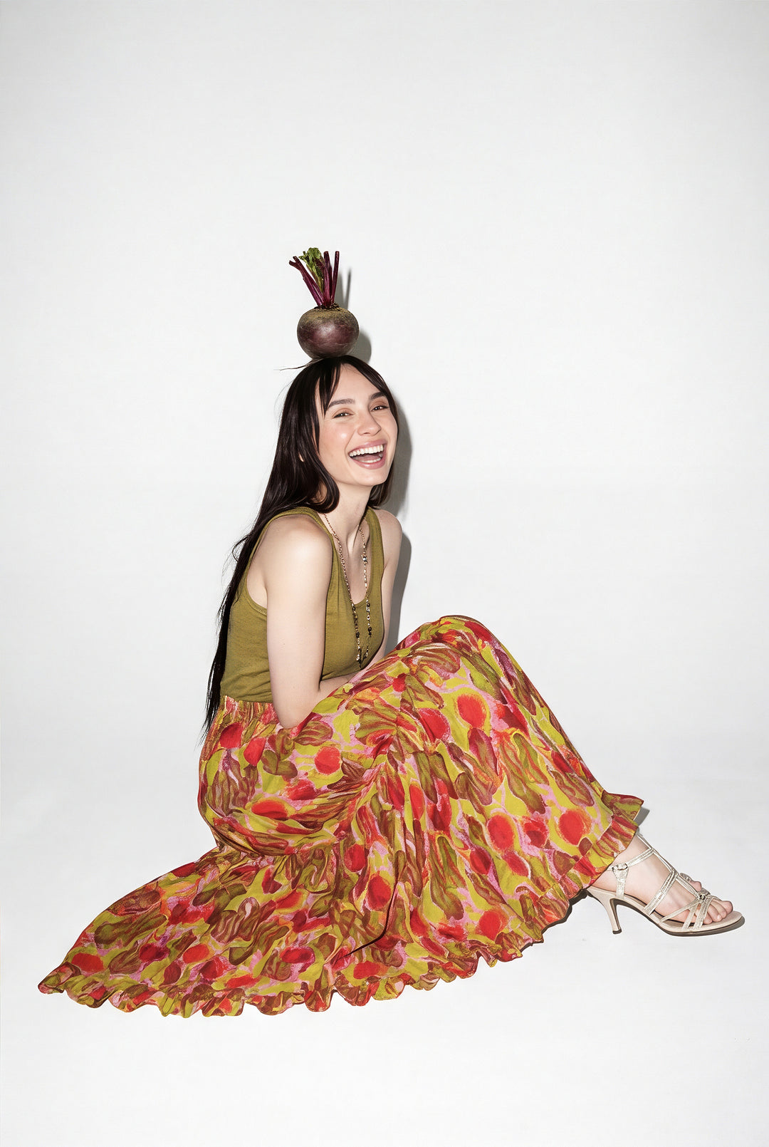 Woman in a colorful dress sitting on the floor with a white background