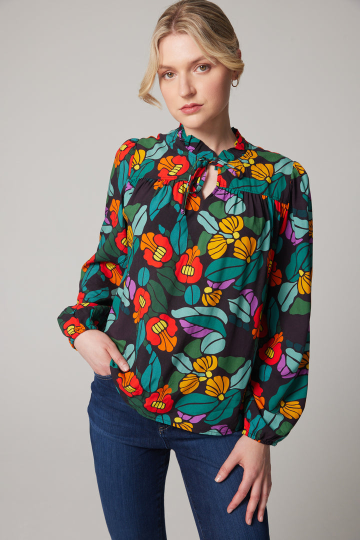 Woman wearing a colorful floral blouse against a plain background
