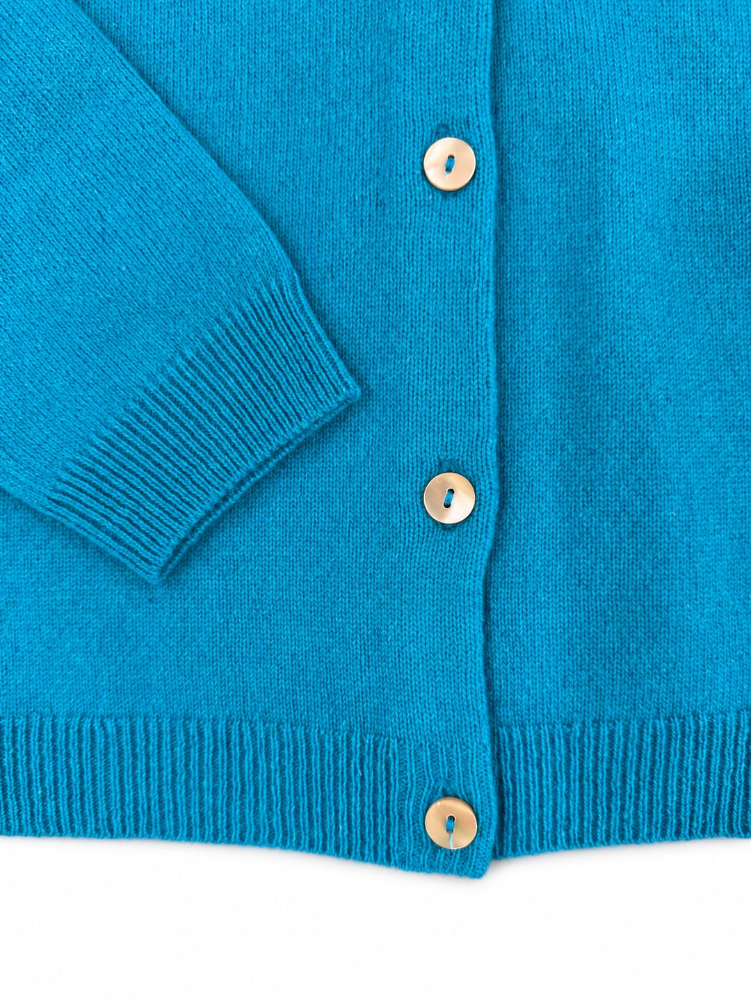 Close-up of the Balmoral turquoise cashmere cardigan cuff, ribbed hem and pearl buttons.