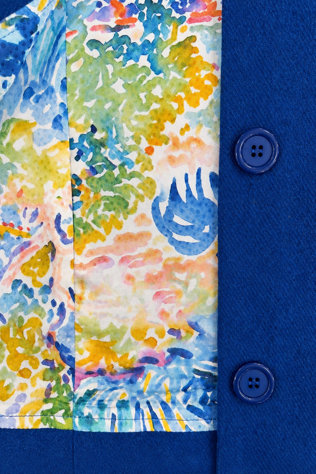 Close-up of the Fairy Coat in Cerulean showing colourful watercolor-print silk lining, blue wool-blend fabric and matching buttons.