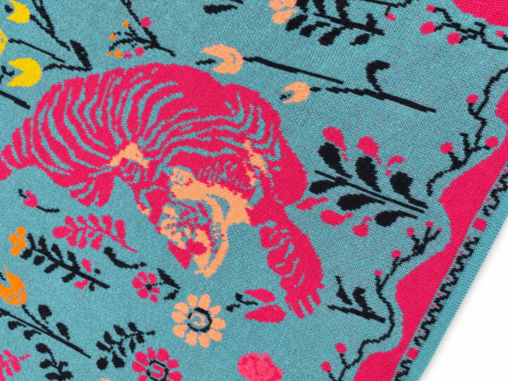 Close-up of the IVKO Wild Garden Adria triangle scarf showing the pink tiger motif, floral pattern and fine knitted texture.
