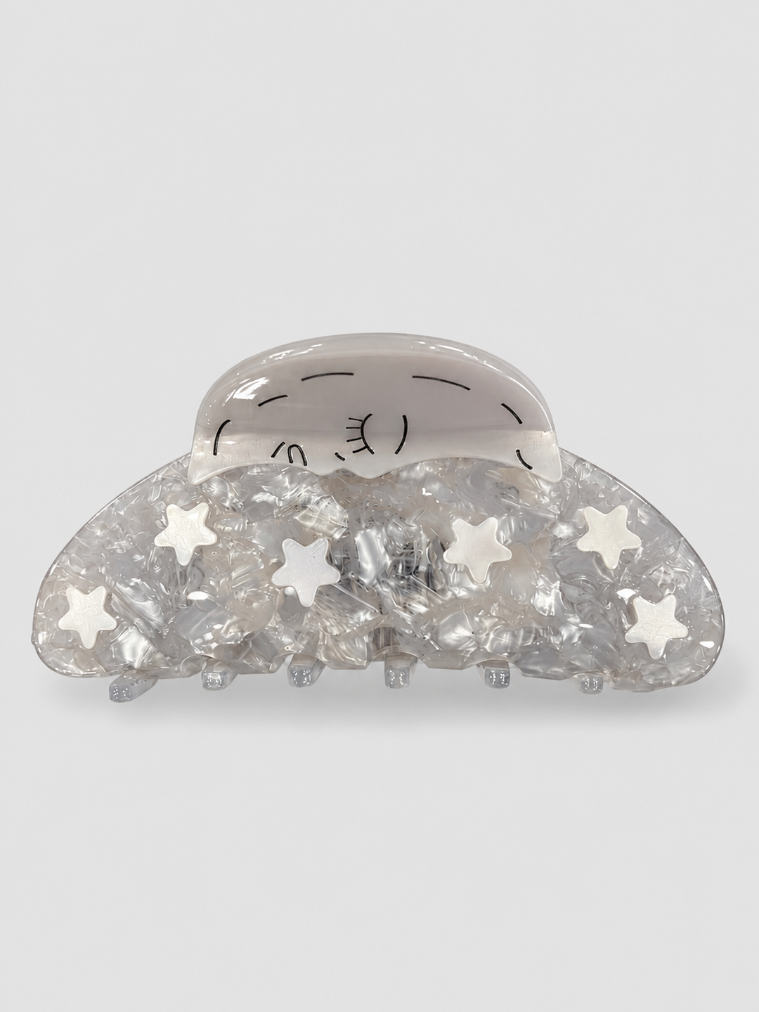 Pearlescent silver hair claw clip with a sleeping crescent moon and six white stars on a pale grey background.