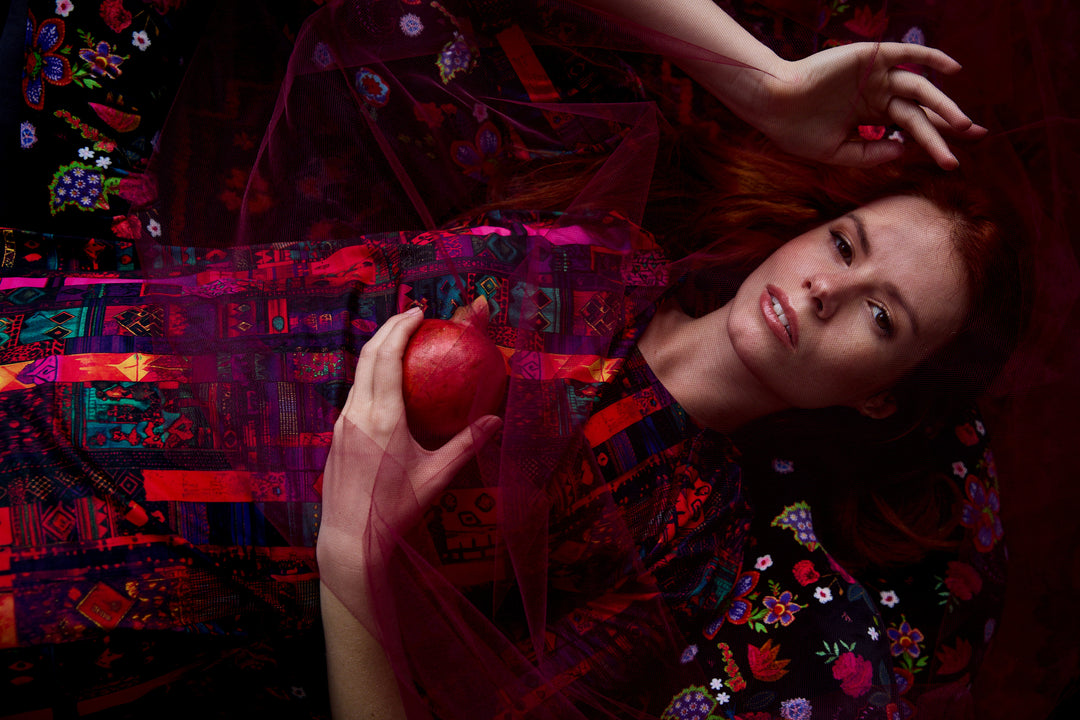 Model wearing Katrin Leblond’s colourful Woven Books print, holding a pomegranate.